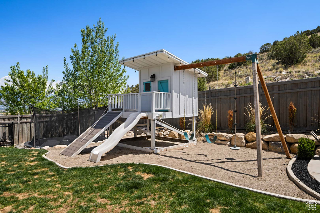 View of play area featuring a lawn and a fenced backyard