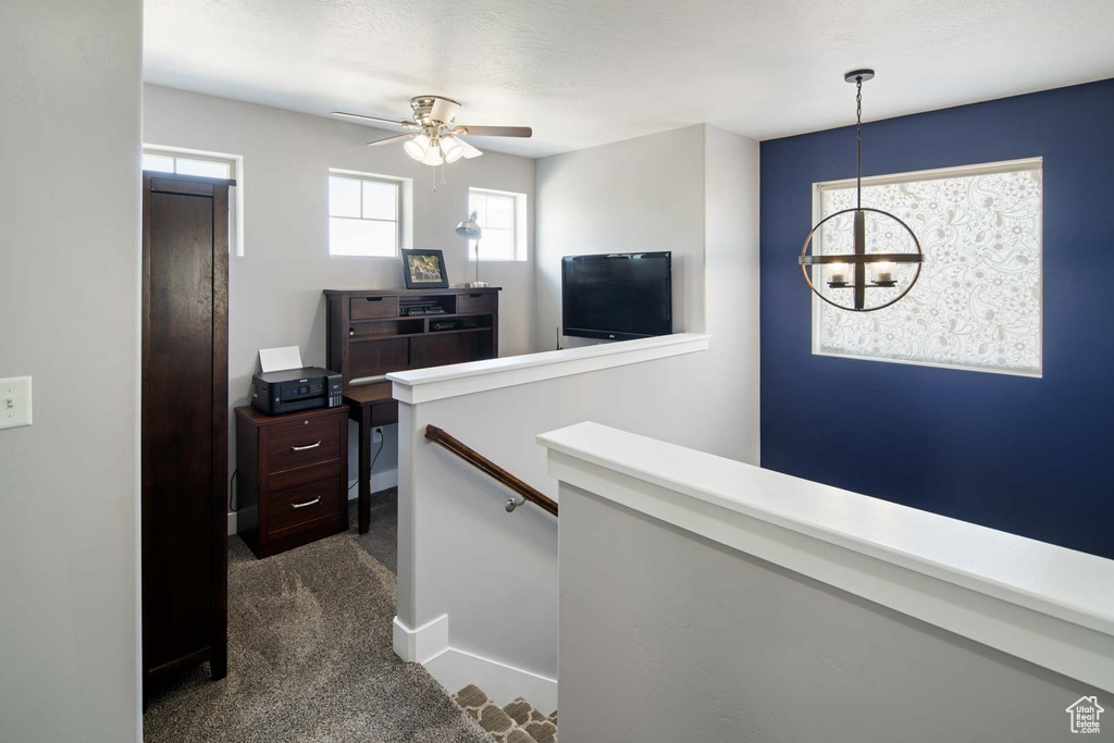 Corridor with dark carpet, baseboards, a notable chandelier, and an upstairs landing