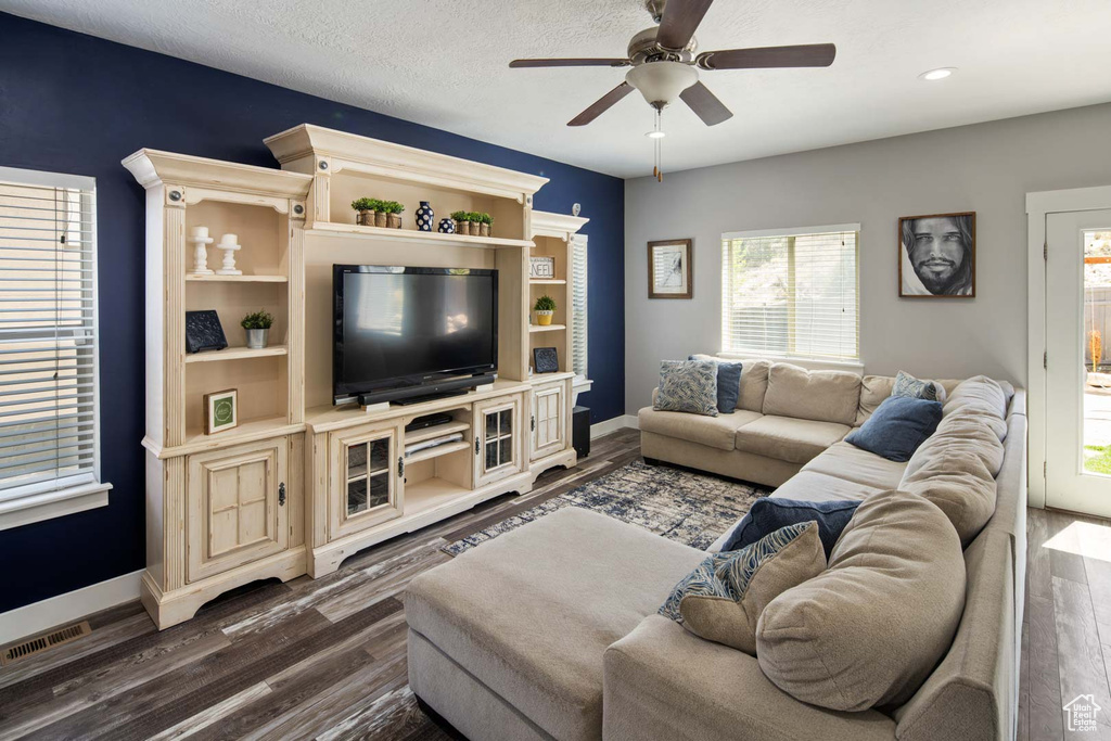 Living room with baseboards, visible vents, a ceiling fan, and dark wood-type flooring