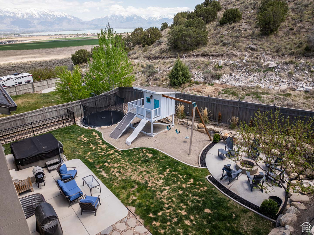 View of yard featuring outdoor lounge area, a fenced backyard, a patio area, a playground, and a mountain view