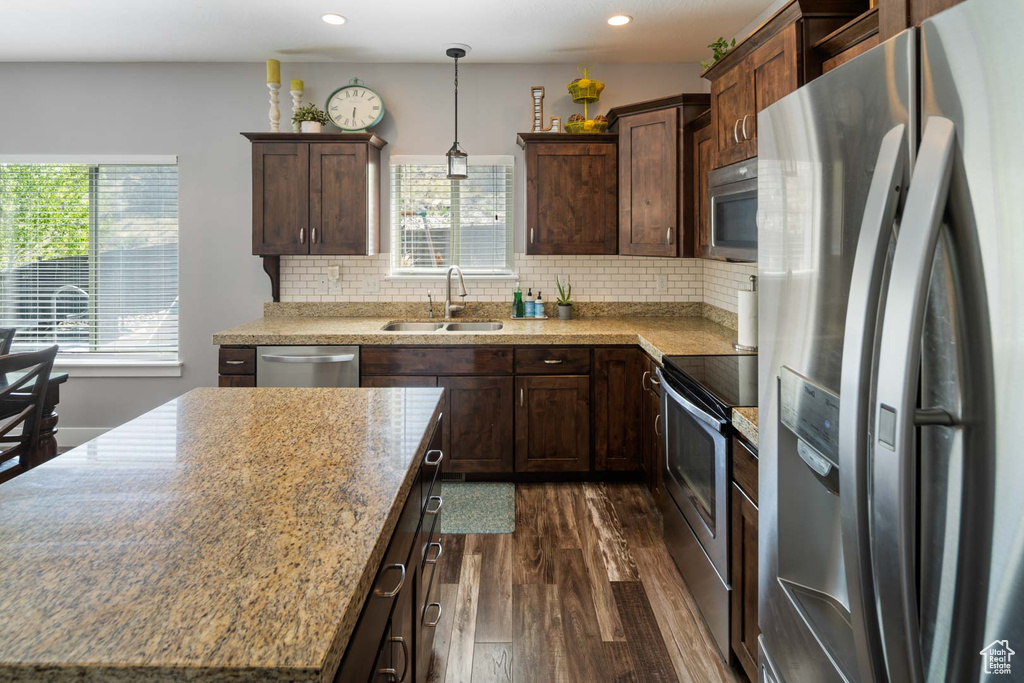 Kitchen with appliances with stainless steel finishes, dark wood finished floors, dark brown cabinets, a sink, and recessed lighting