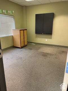 Empty room featuring baseboards, light colored carpet, and a paneled ceiling