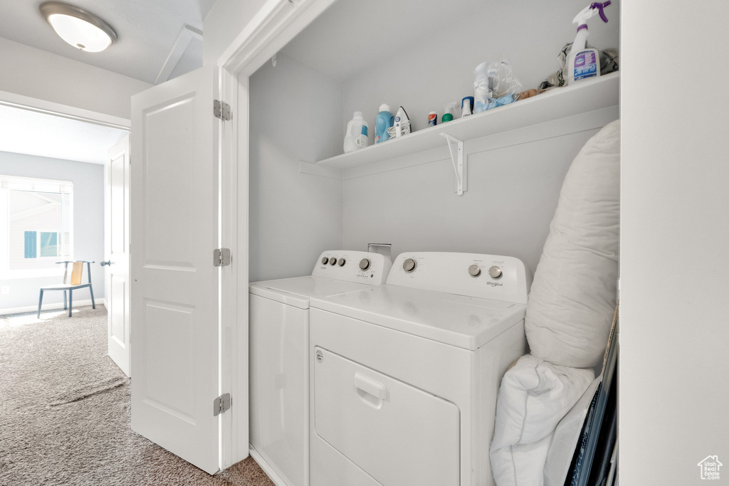 Clothes washing area featuring laundry area, washing machine and dryer, and light colored carpet