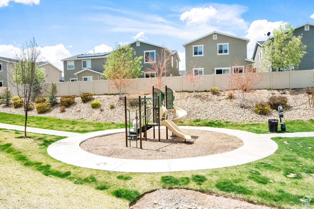 Communal playground featuring fence, a yard, and a residential view