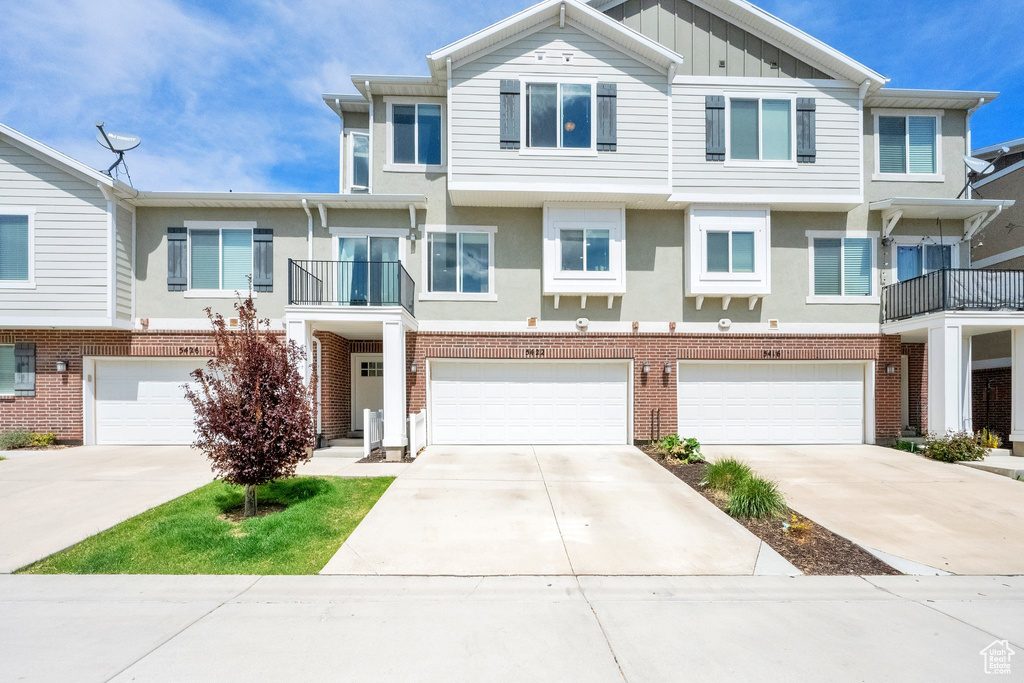Townhome / multi-family property featuring an attached garage, board and batten siding, stucco siding, and concrete driveway