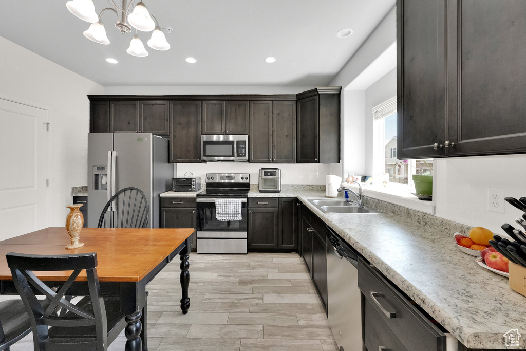 Kitchen featuring an inviting chandelier, a sink, light countertops, stainless steel appliances, and recessed lighting