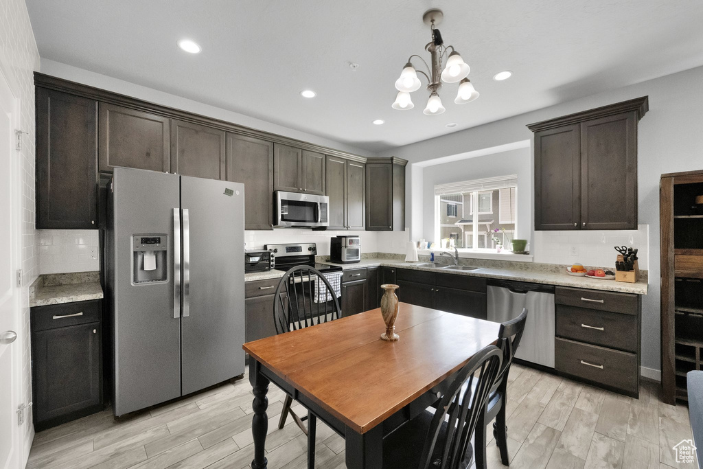 Kitchen with stainless steel appliances, a sink, light wood-style flooring, and dark brown cabinets