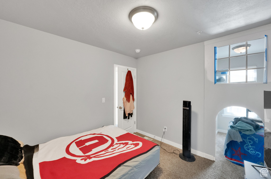 Bedroom featuring a textured ceiling, baseboards, and carpet