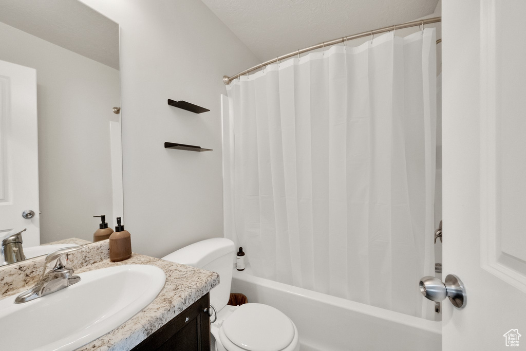 Full bath featuring vanity, shower / bath combo with shower curtain, and toilet