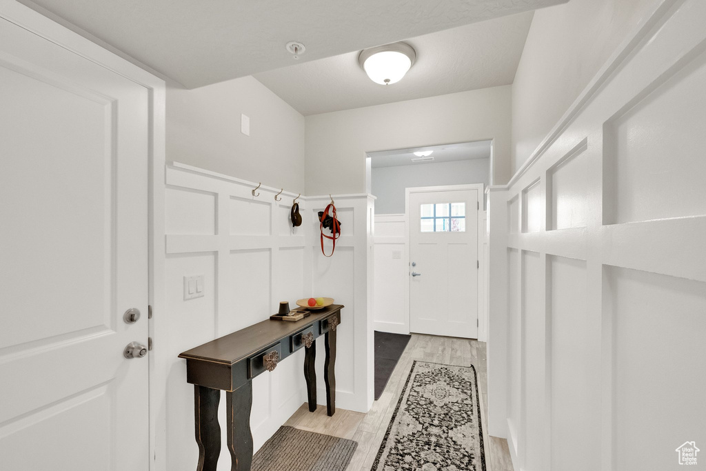Entryway with wainscoting, light wood-style flooring, and a decorative wall