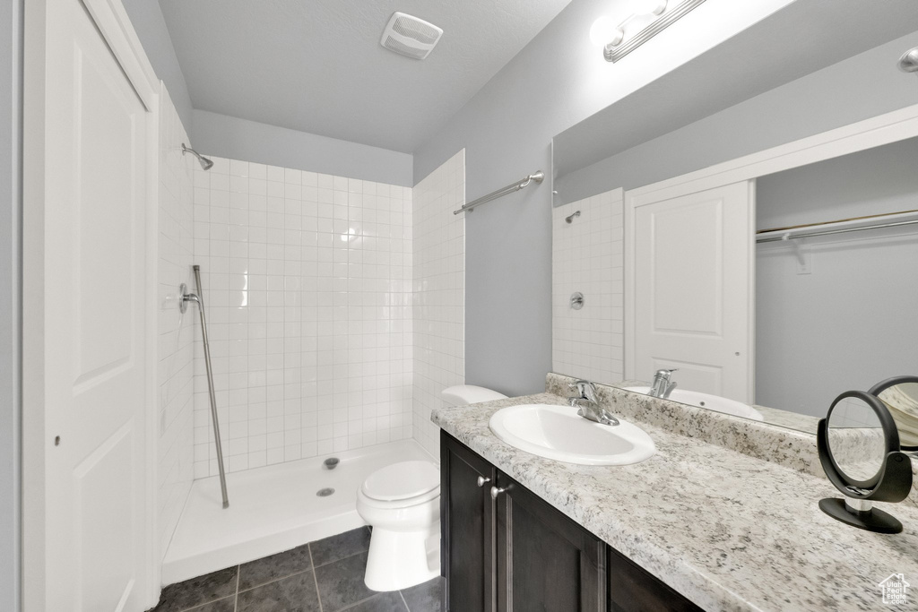 Full bath with a tile shower, vanity, toilet, tile patterned floors, and visible vents