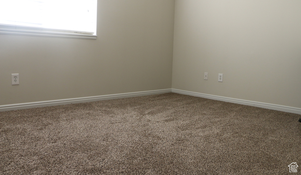 Carpeted empty room featuring baseboards