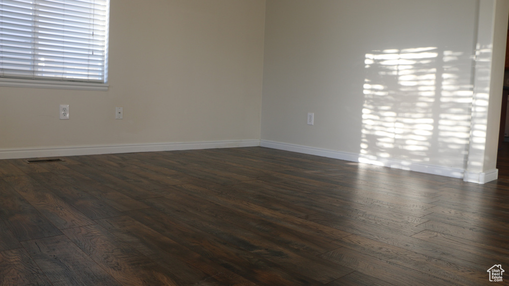 Spare room with visible vents, dark wood finished floors, and baseboards