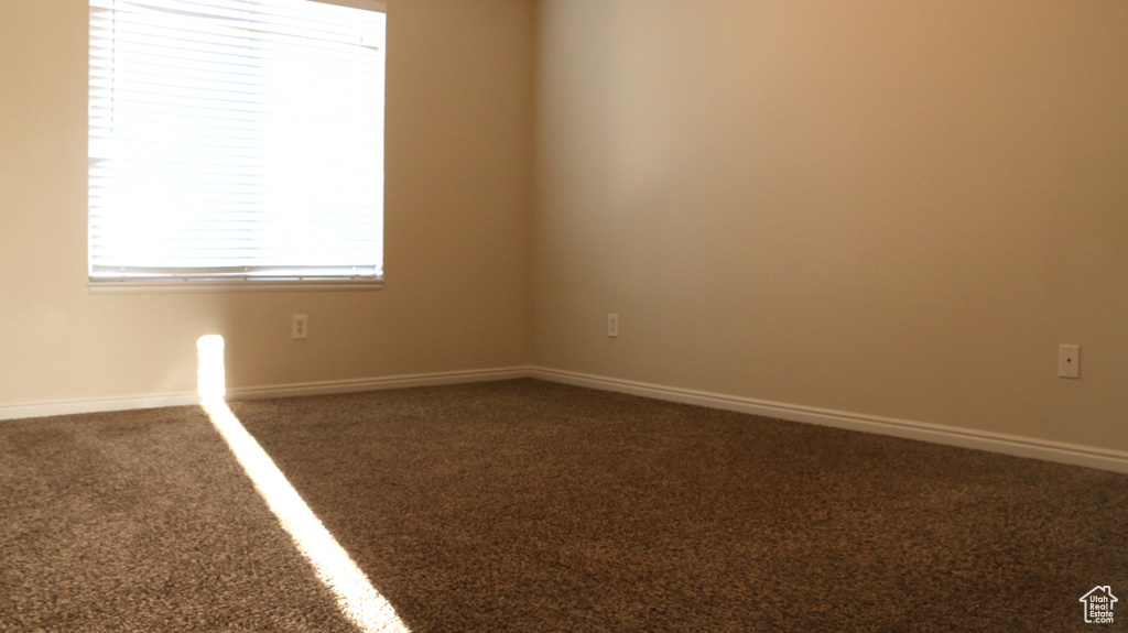 Carpeted spare room featuring baseboards