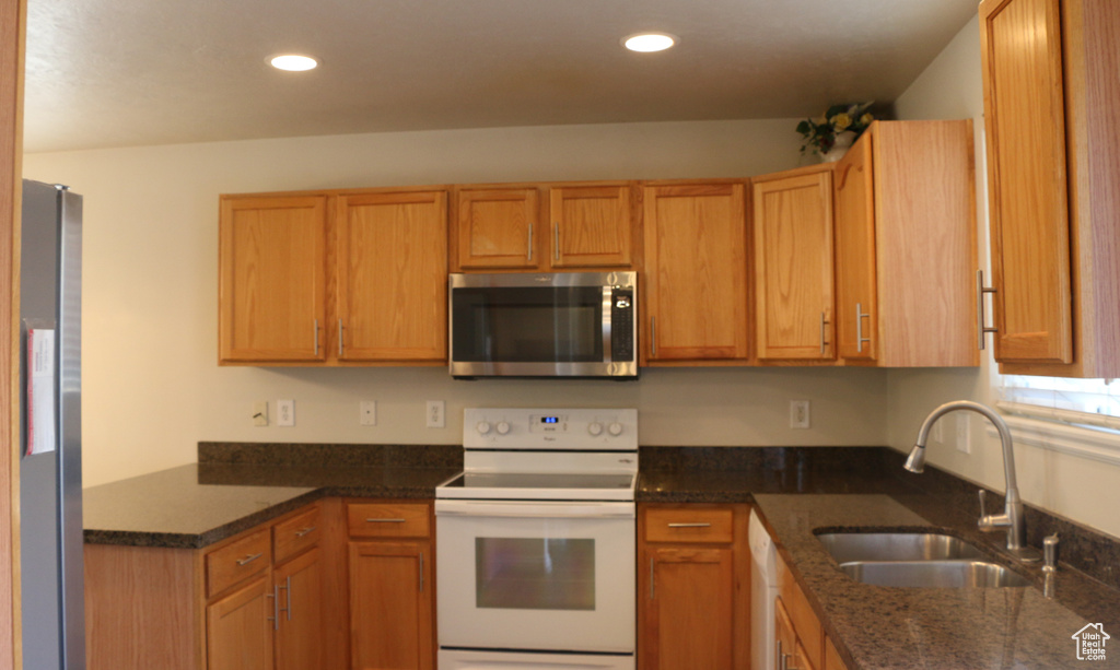 Kitchen featuring a sink, dark stone countertops, stainless steel appliances, and recessed lighting