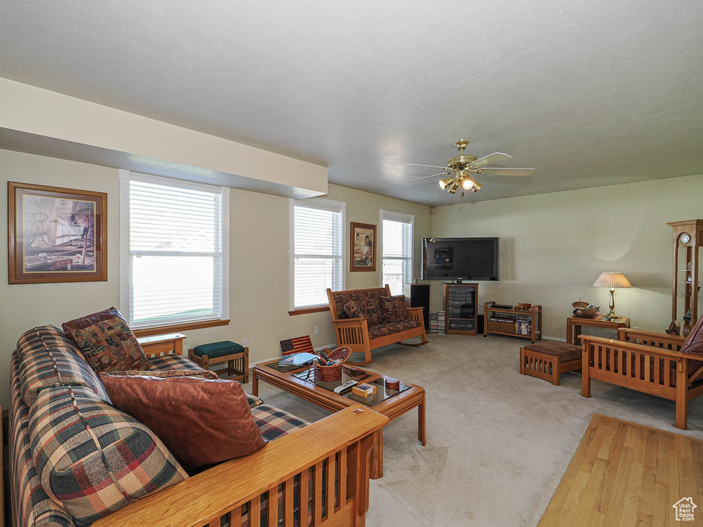 Living area featuring light colored carpet and a ceiling fan