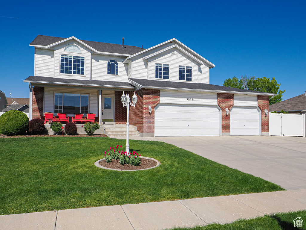 Traditional-style house featuring driveway, brick siding, fence, a front lawn, and outdoor lounge area