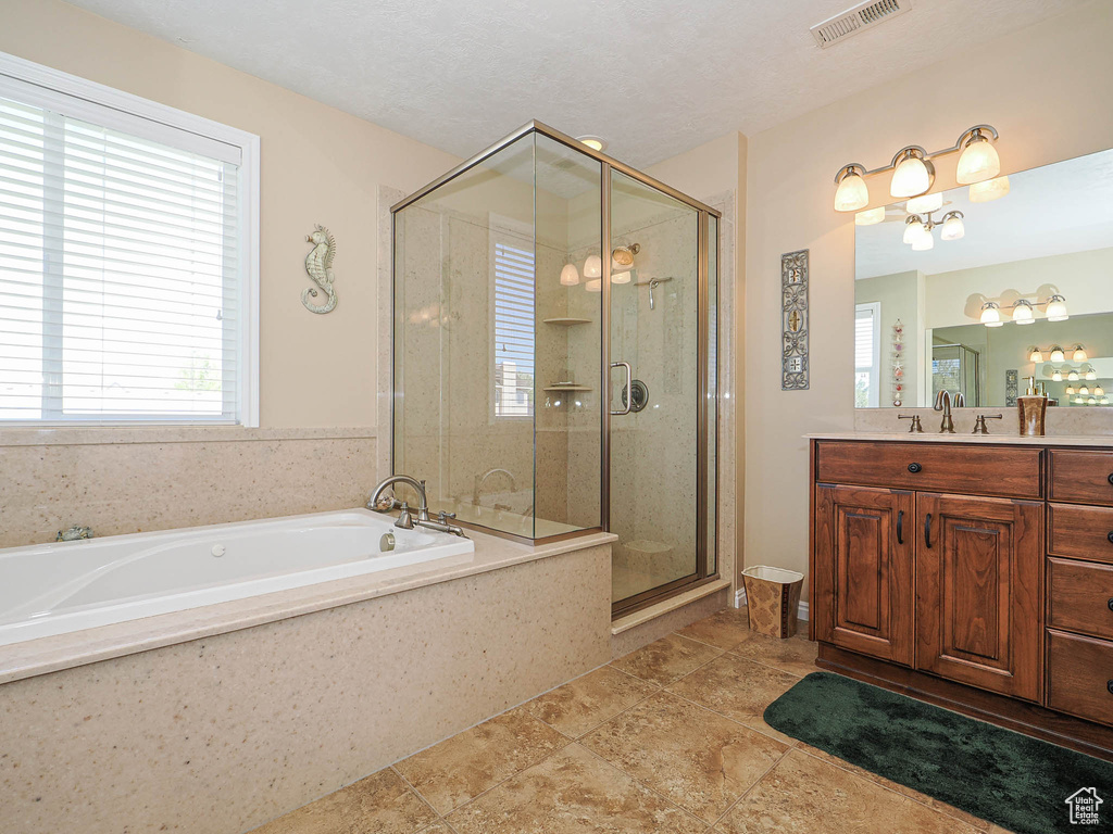Full bathroom featuring vanity, a shower stall, a garden tub, and visible vents