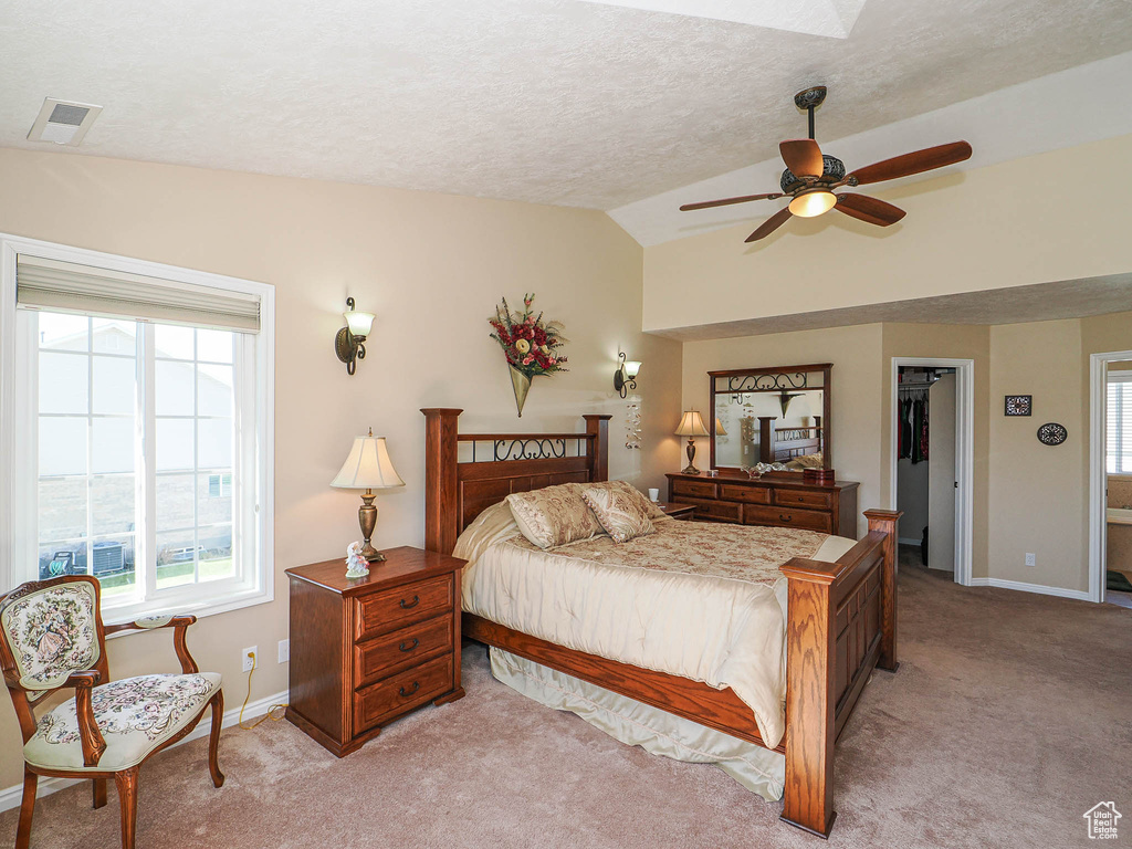 Bedroom featuring visible vents, lofted ceiling, baseboards, a walk in closet, and light colored carpet
