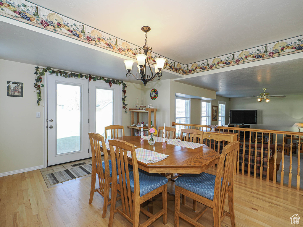 Dining area featuring baseboards, light wood finished floors, and ceiling fan with notable chandelier