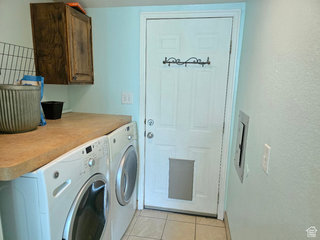 Laundry area with light tile patterned floors, independent washer and dryer, and cabinet space