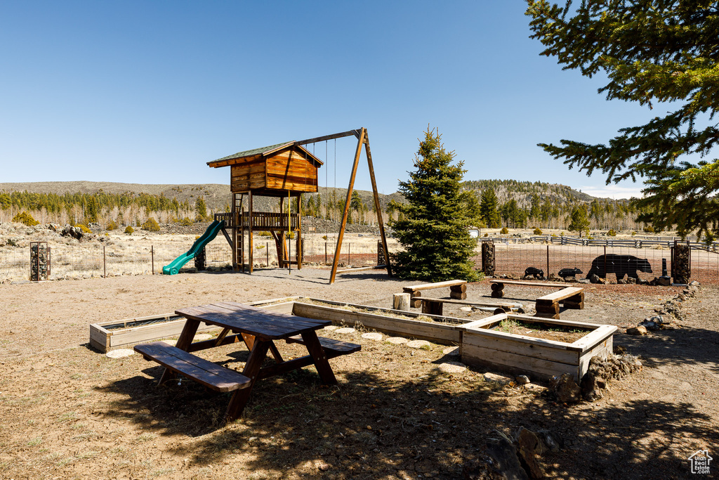 Community jungle gym featuring fence and a mountain view