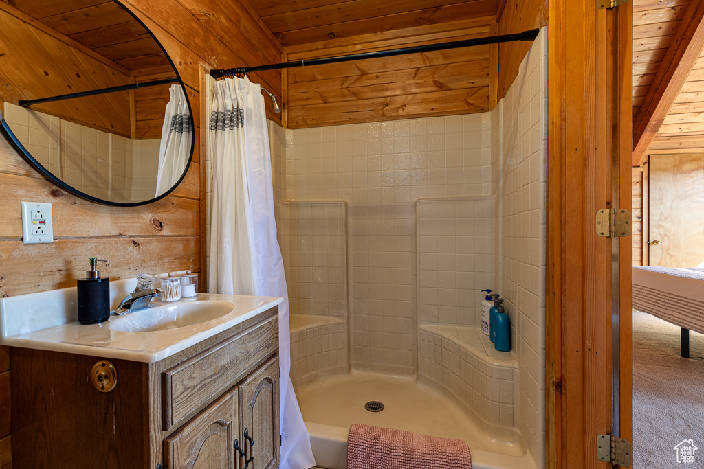 Full bath featuring vanity, wood walls, a shower with shower curtain, and wooden ceiling
