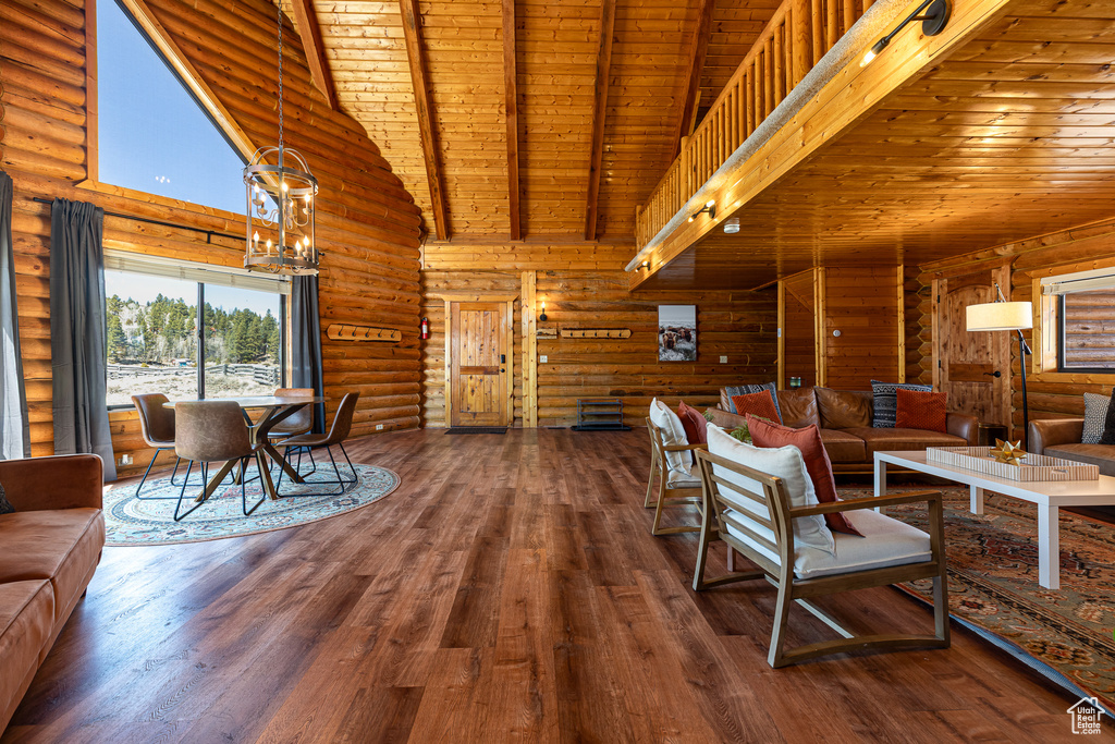 Living area featuring beamed ceiling, log walls, wood ceiling, and high vaulted ceiling