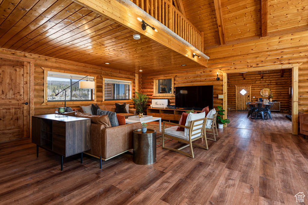 Living room with beam ceiling, wooden ceiling, rustic walls, and wood finished floors