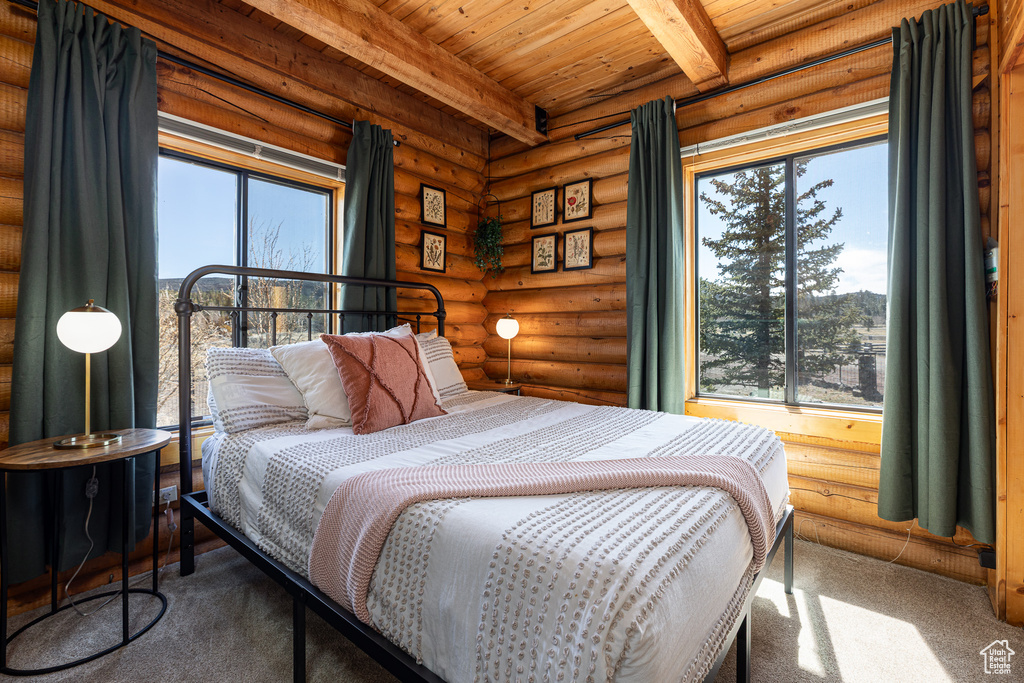 Bedroom with carpet flooring, wood ceiling, rustic walls, and beam ceiling