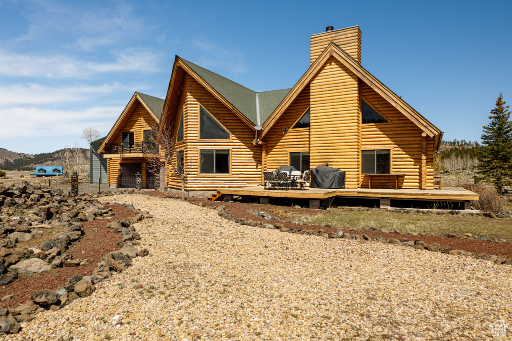 Exterior space with a wooden deck, a chimney, and log siding