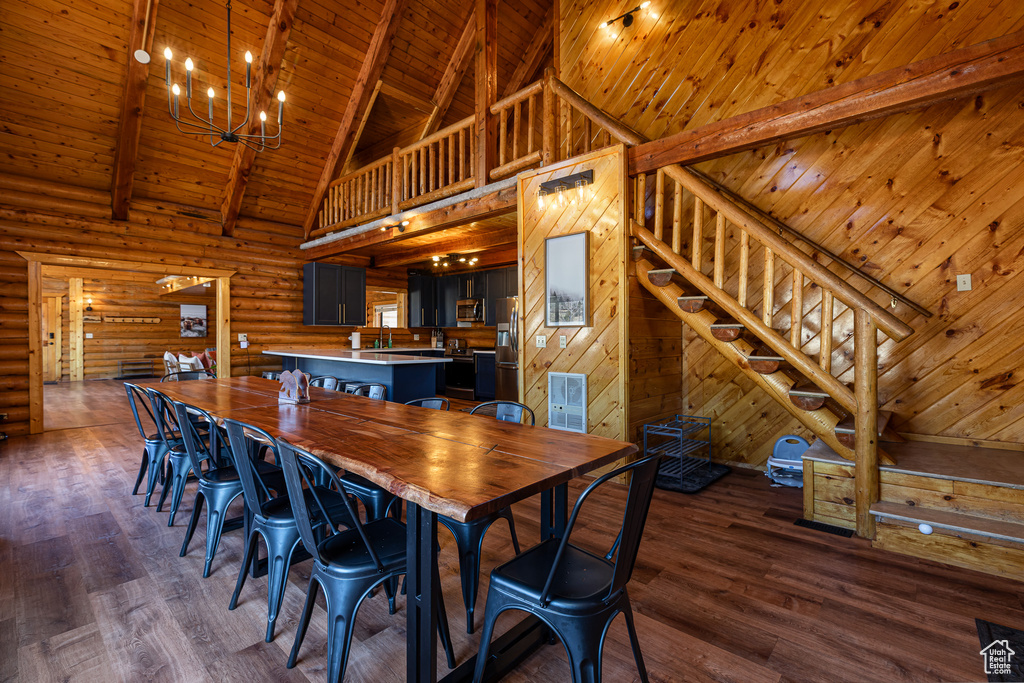 Dining area with dark wood-style flooring, stairs, beamed ceiling, high vaulted ceiling, and wooden ceiling