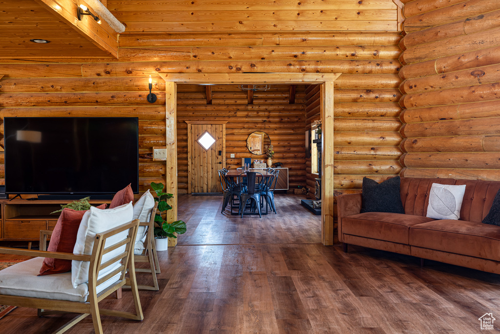 Living area featuring wooden ceiling, log walls, hardwood / wood-style flooring, and beam ceiling