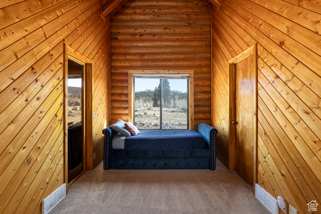 Bedroom with visible vents, carpet, and log walls