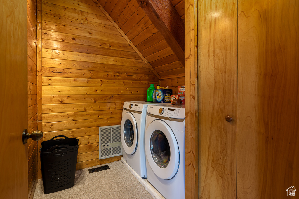 Clothes washing area with laundry area, carpet floors, wooden walls, wooden ceiling, and separate washer and dryer