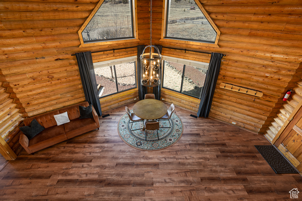 Room details with log walls, an inviting chandelier, and wood finished floors