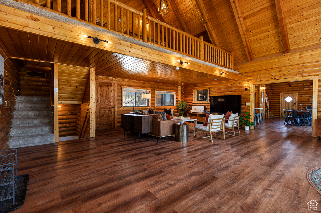 Living area with wood ceiling, beam ceiling, wood finished floors, high vaulted ceiling, and log walls