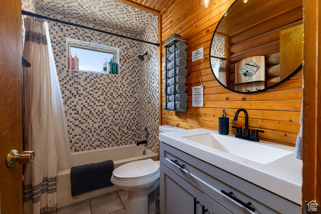 Full bathroom featuring shower / bath combination with curtain, tile patterned flooring, vanity, toilet, and wooden walls