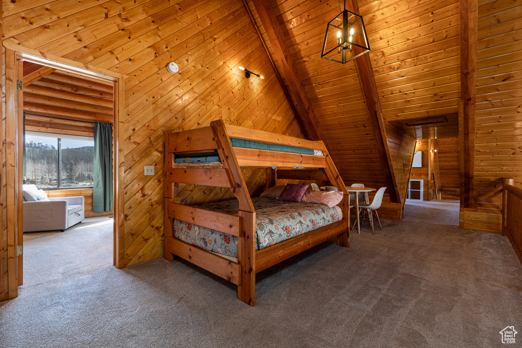 Bedroom with wooden walls, carpet floors, vaulted ceiling with beams, and wood ceiling