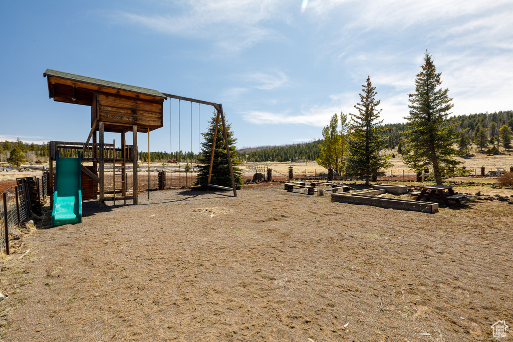 Community jungle gym with a rural view and fence
