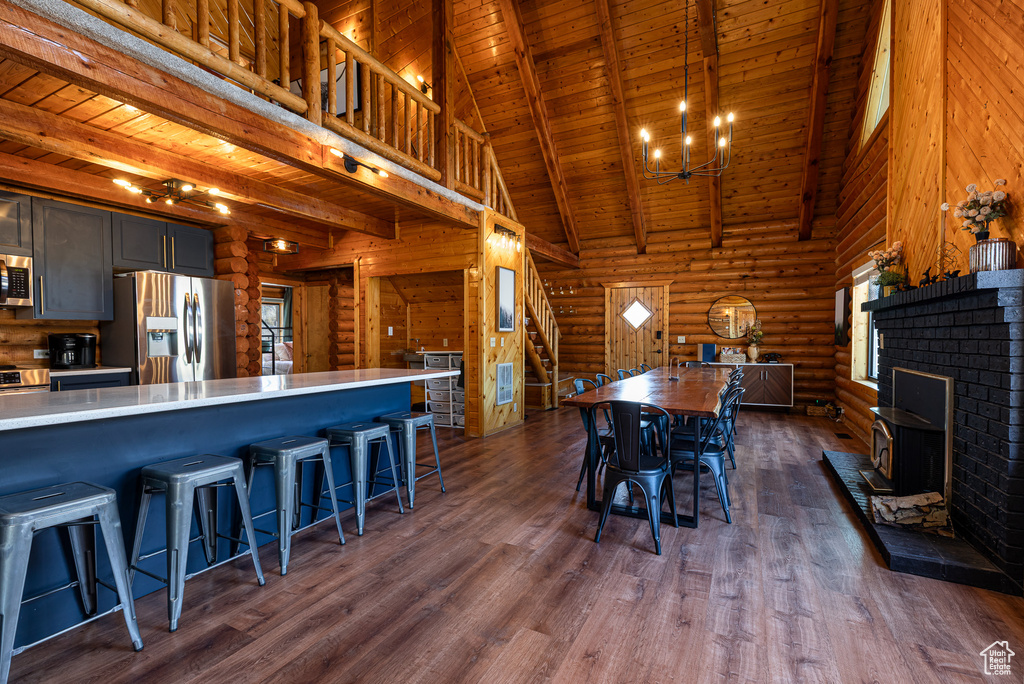 Dining space featuring beam ceiling, wooden ceiling, log walls, a high ceiling, and stairs
