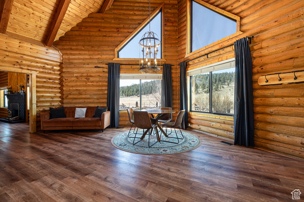 Dining area featuring beam ceiling, wooden ceiling, high vaulted ceiling, a notable chandelier, and log walls
