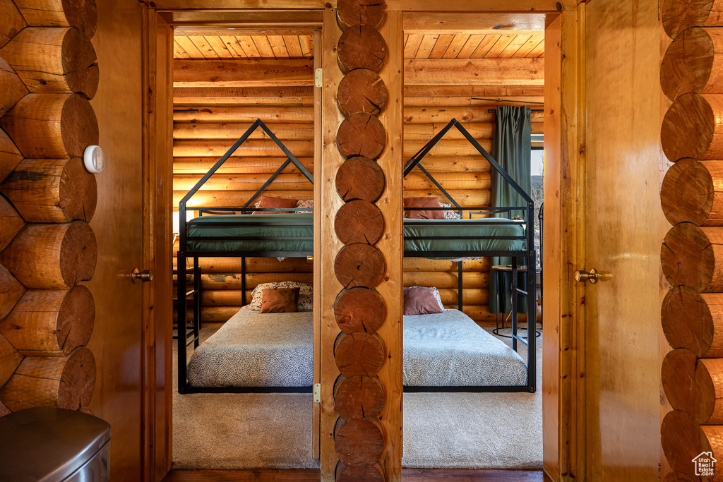 Interior space featuring beamed ceiling, wood ceiling, rustic walls, and wood finished floors