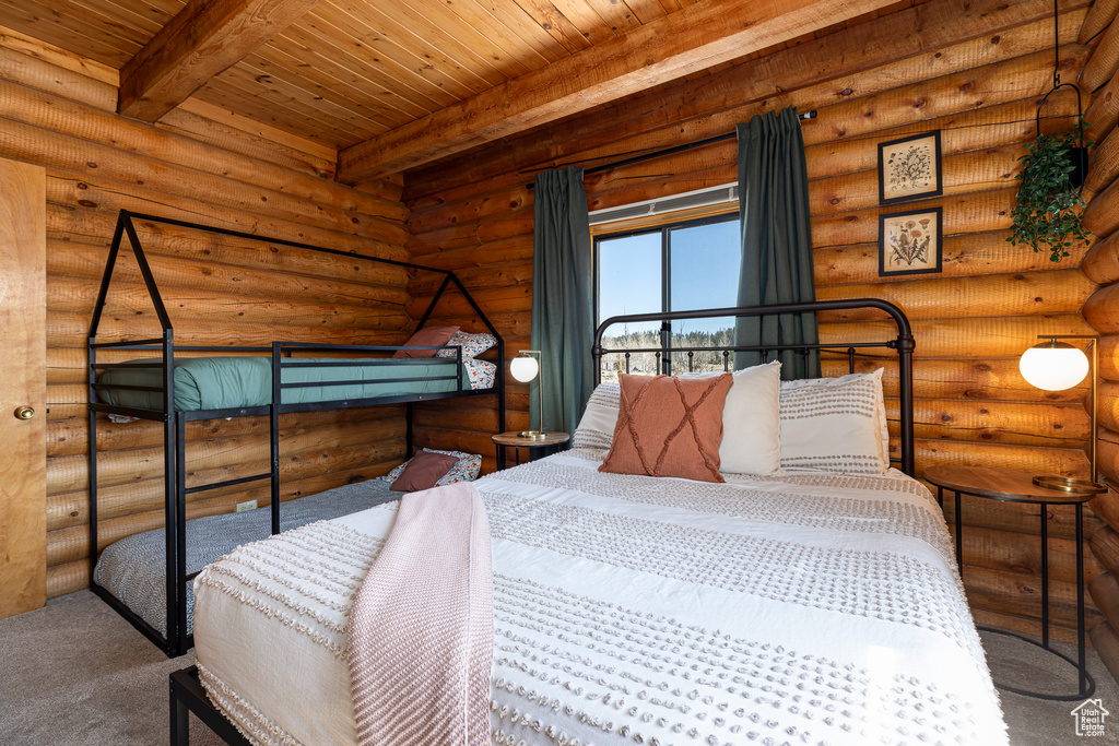 Carpeted bedroom with beamed ceiling, wood ceiling, and rustic walls