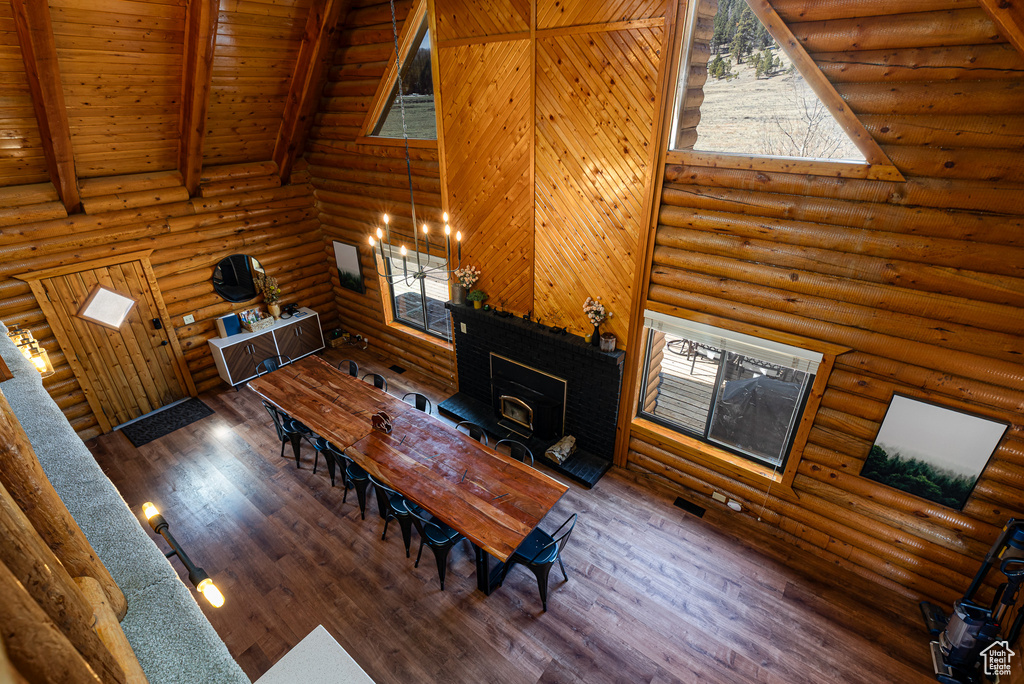 Dining area with a wood stove, beam ceiling, wood finished floors, wooden ceiling, and high vaulted ceiling