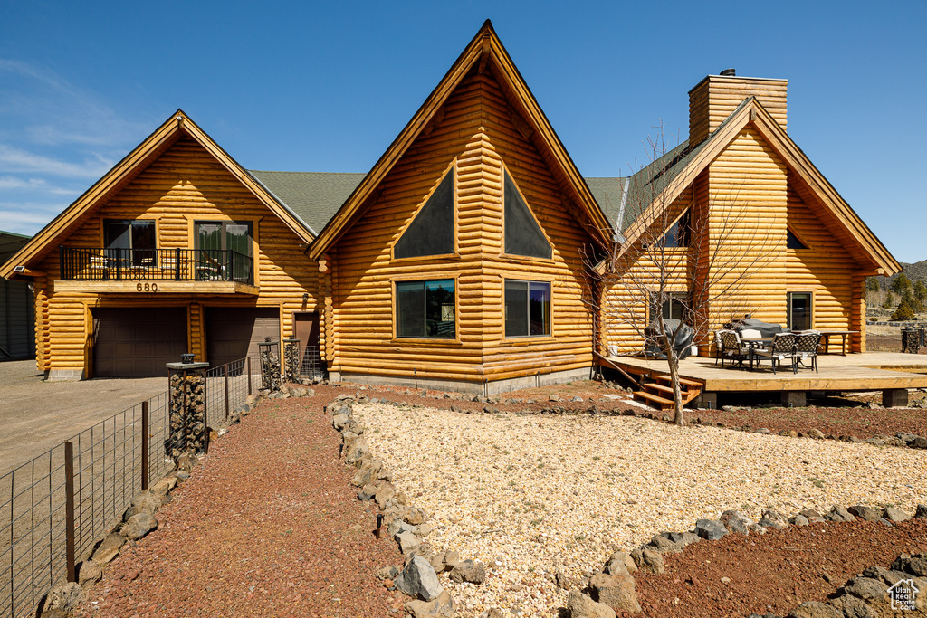 View of front of property featuring an attached garage, log siding, and a chimney