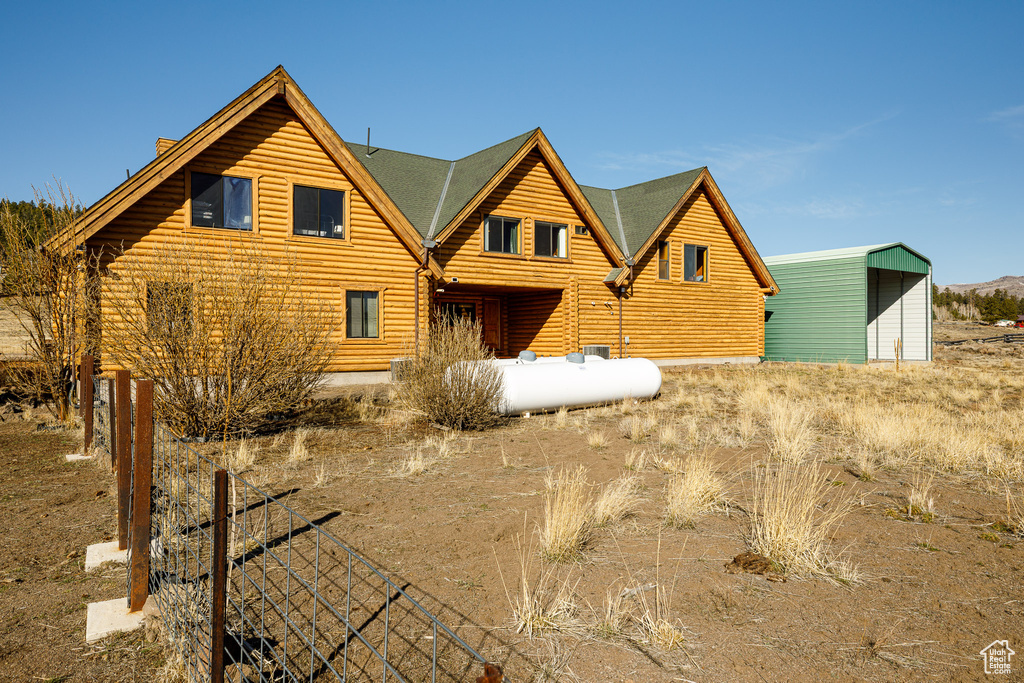 Rear view of property with roof with shingles and an outdoor structure