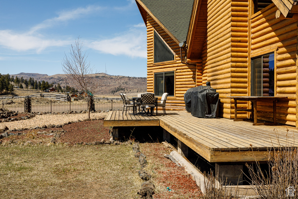 Wooden deck with fence, a mountain view, and a grill