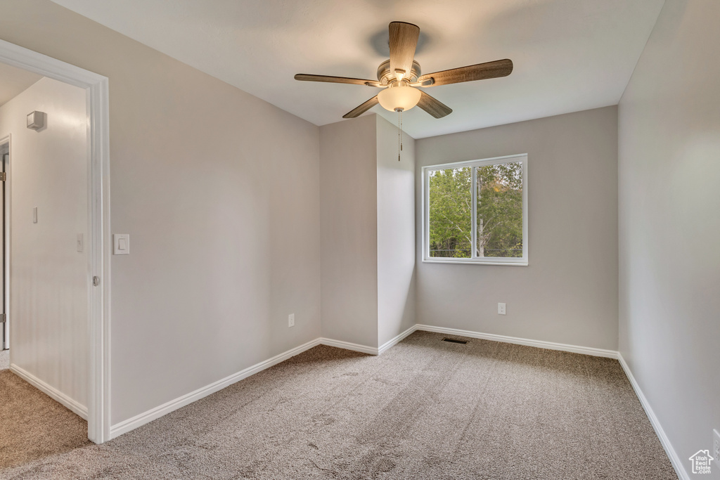 Spare room with carpet flooring, a ceiling fan, and baseboards