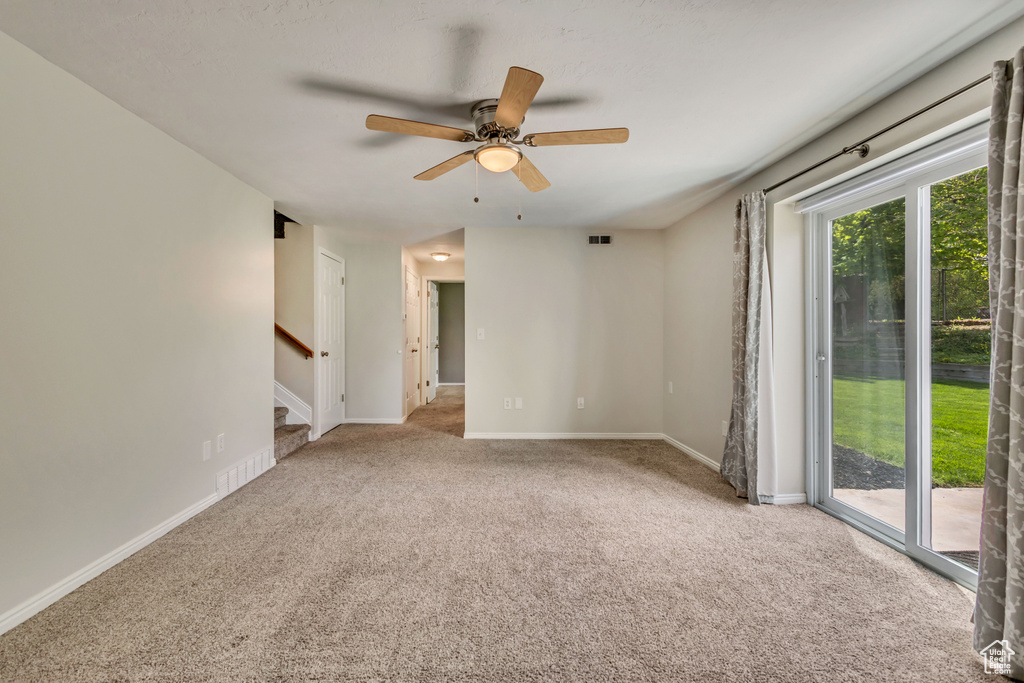 Spare room featuring carpet floors, stairs, ceiling fan, and baseboards